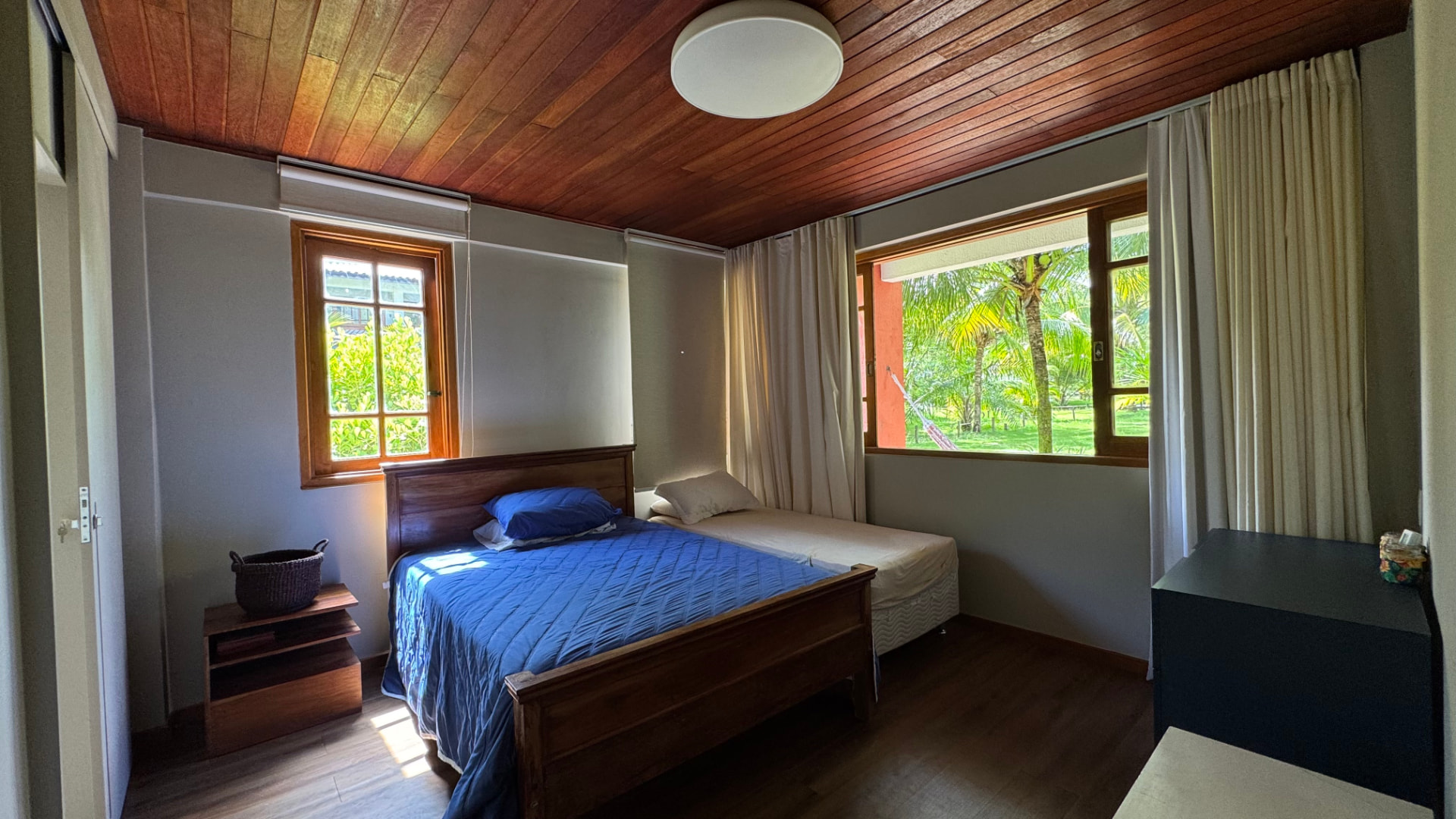 Quarto com teto de madeira e vista para o verde